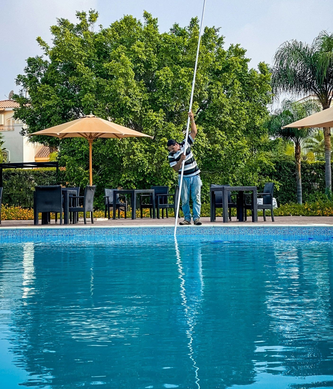 Pool technician skimming a residential swimming pool